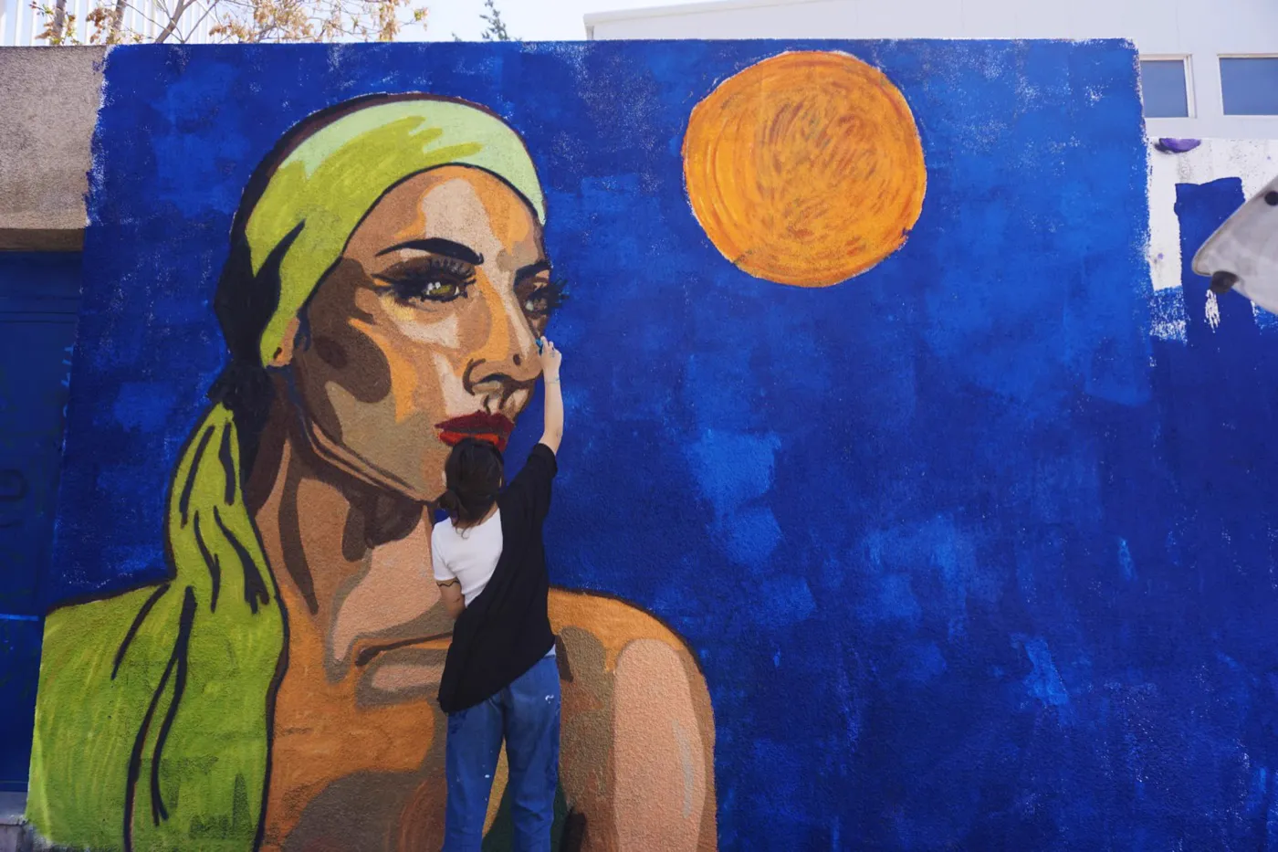 Randa painting a large outdoor mural